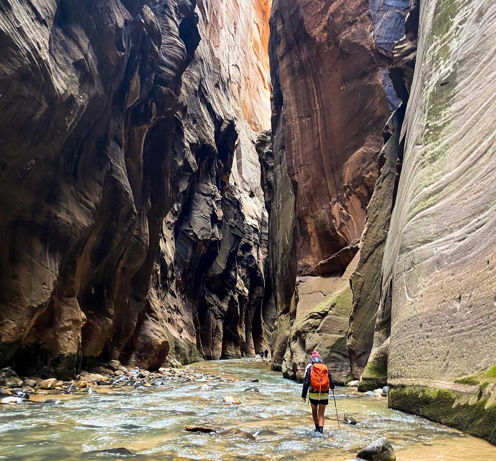 woman with orange osprey backpack hiking the narrows in zion national park